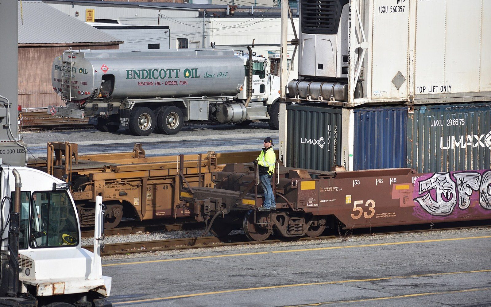 An intermodal train of double-stack well cars alongside a yard