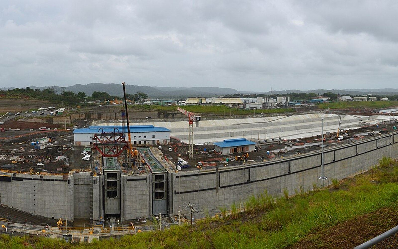 Concrete lock chambers under construction with cranes and worksite buildings nearby