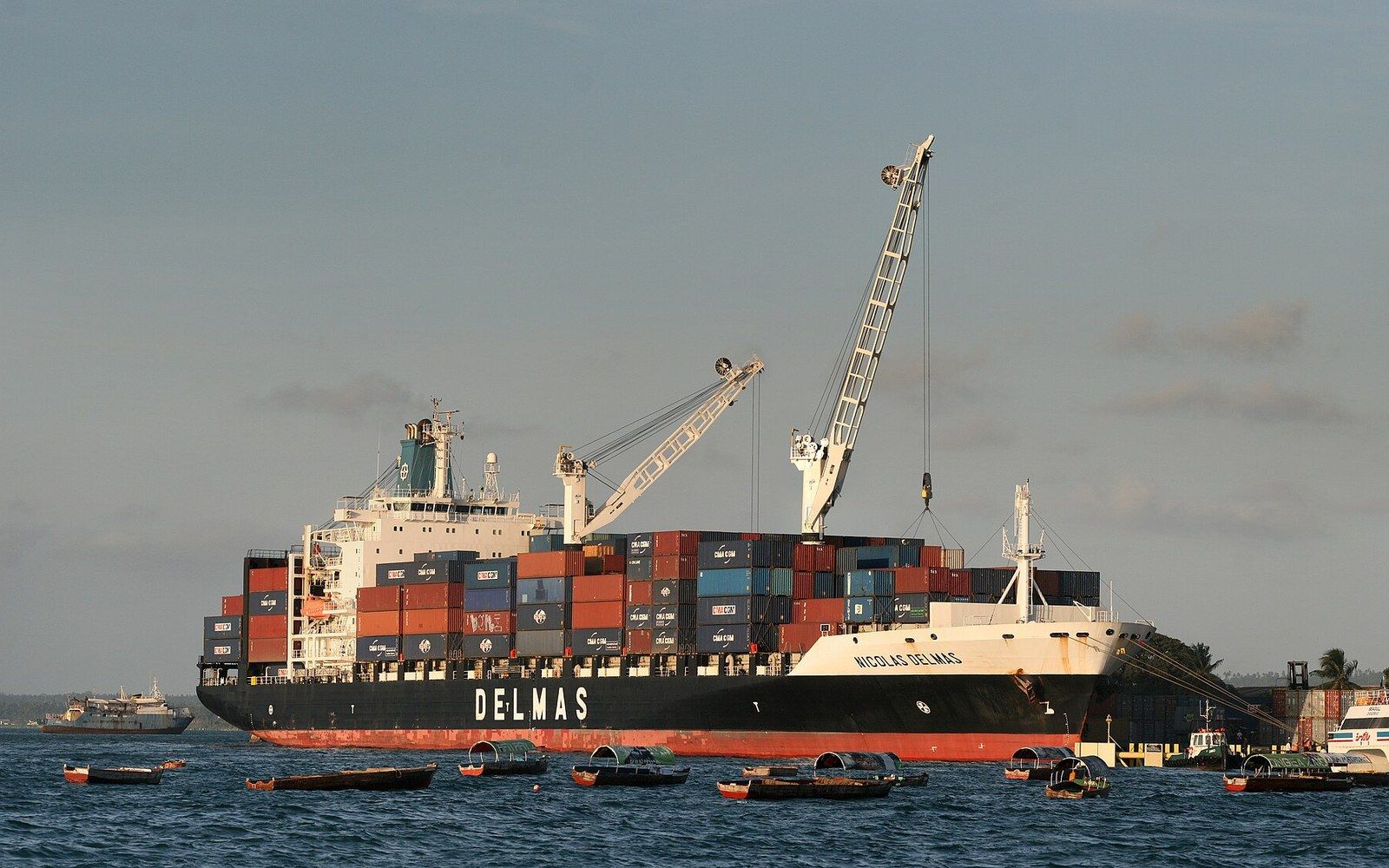The Delmas container ship anchored near shore with small boats nearby